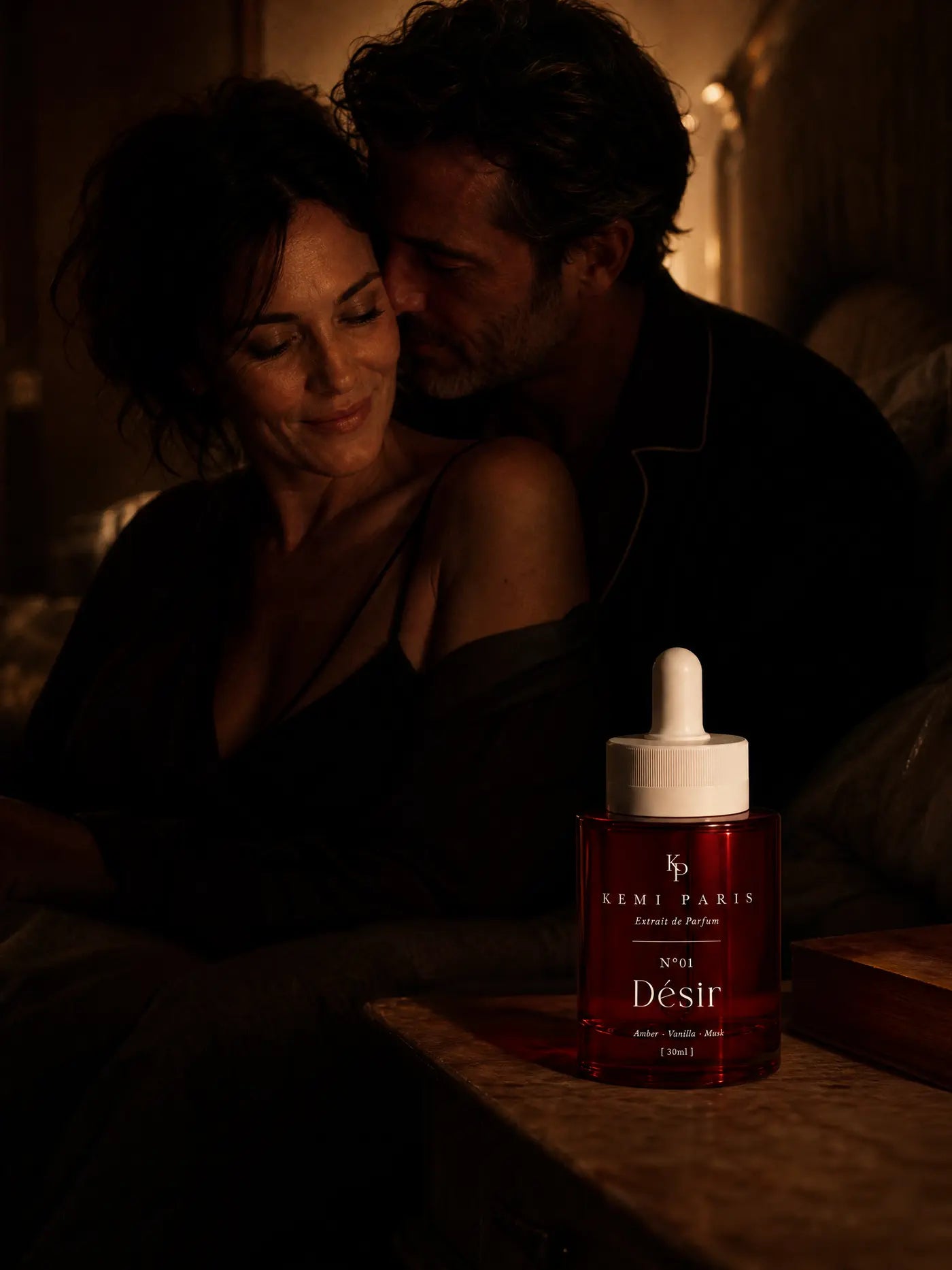 A couple close together in low lamplight, his face at her neck