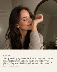 Woman smelling Désir on her own wrist, five star review: warm and a bit smoky, and nobody can place it